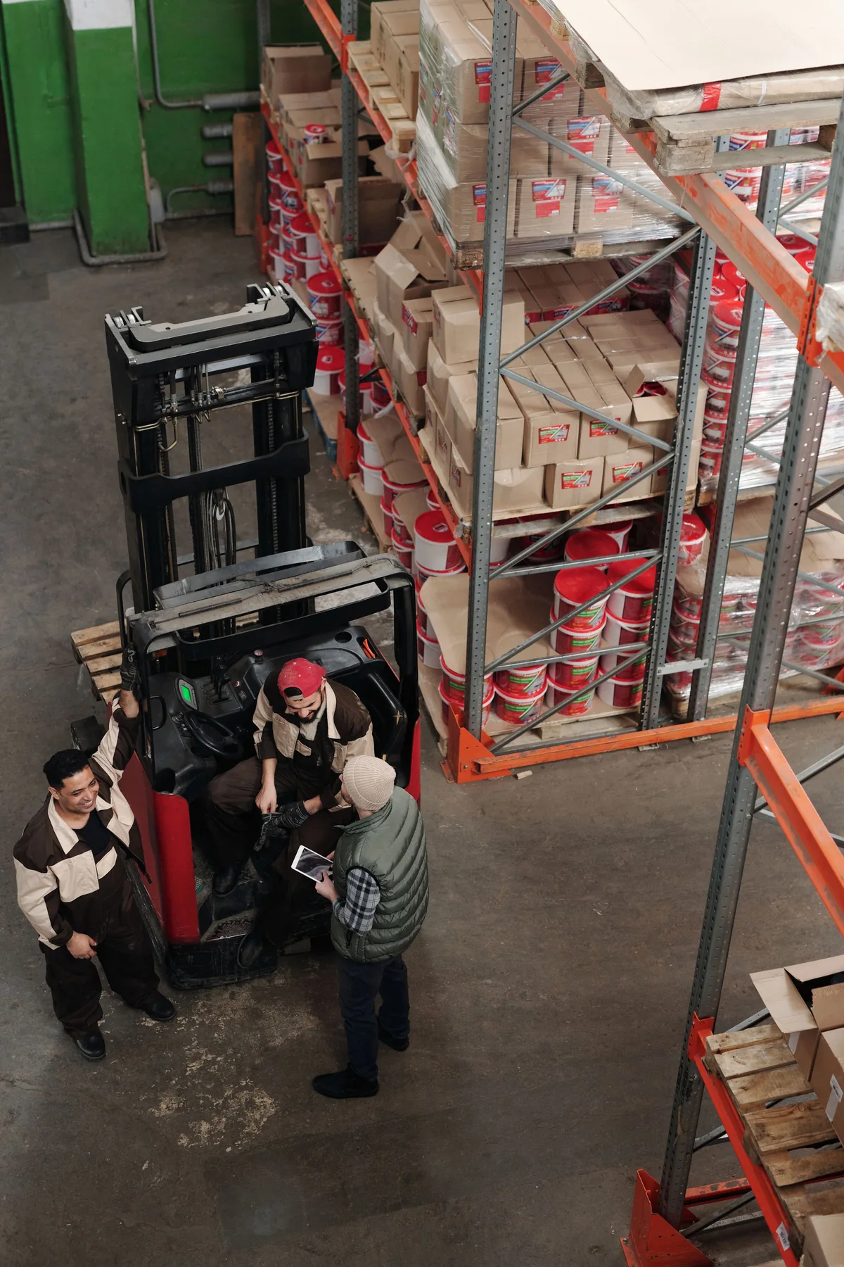 Overhead view of workers beside a forklift and pallet racks in a warehouse.